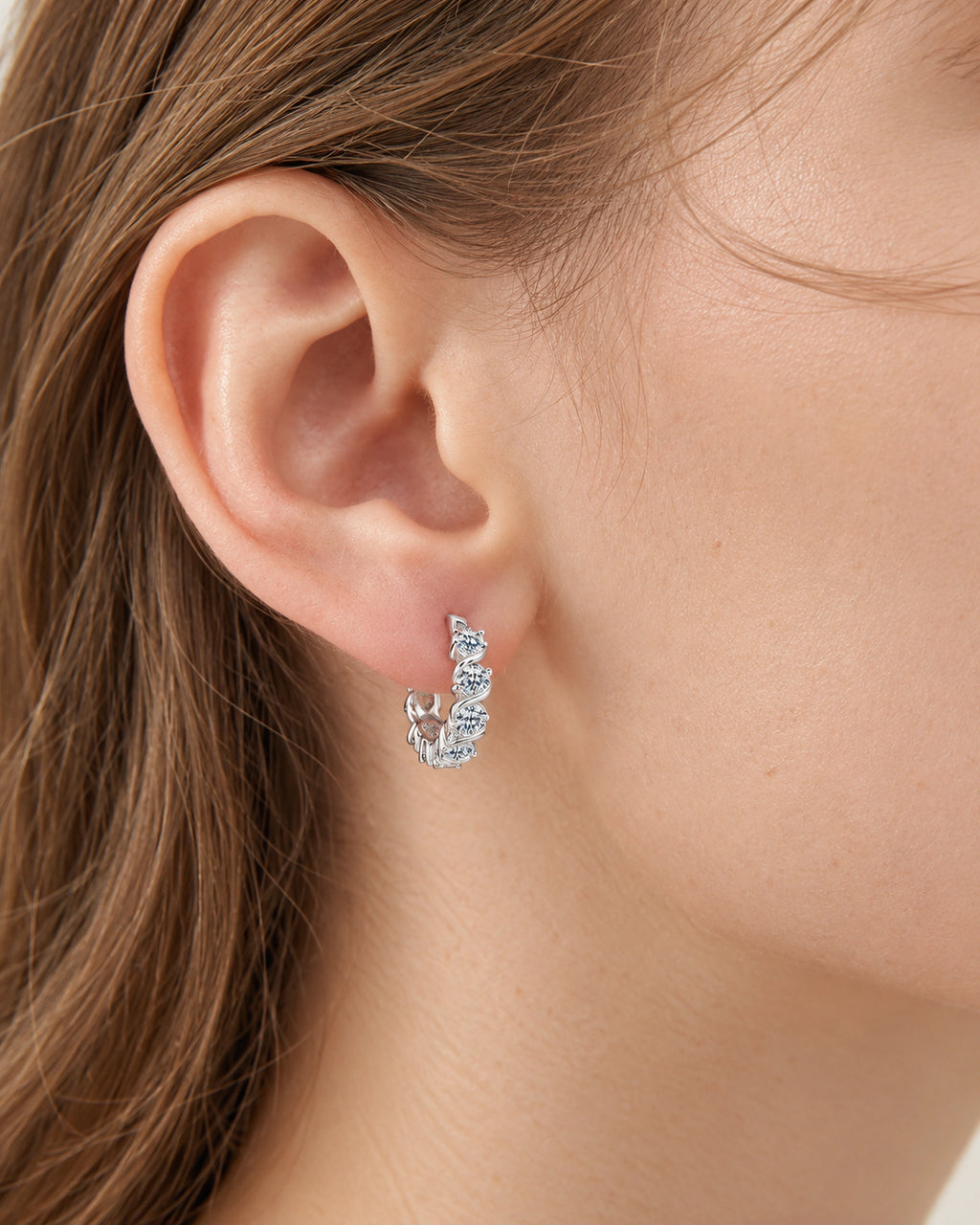 Silver Noelle twist-set moissanite hoop earring worn on an adult ear
