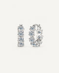 Silver Noelle hoop earrings with round moissanite stones framed by diagonal ribbon settings